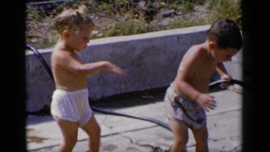 1951: two funny and naughty boys standing on the terrace with a hose to collect