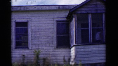 1951: woman leaves her house with a bag while child sits in a chair relaxing