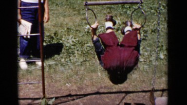 1951: child does front and back somersault on play equipment in back garden.