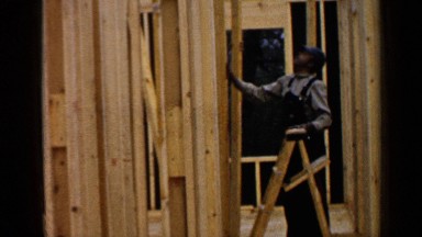 1957: men are seen framing a new house, working on the walls and the roof