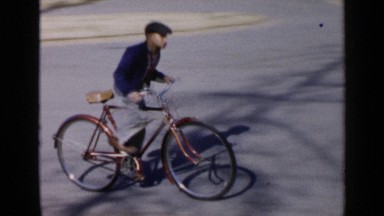 1957: three kids are doing cycle riding fast on the main road at morning time