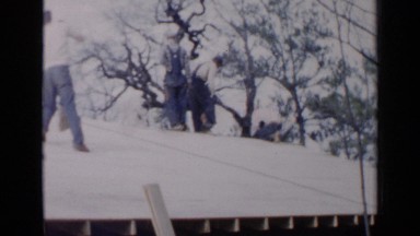 1957: a team of construction workers on a rooftop in 1920s, on a sunny morning
