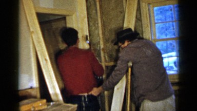 1957: a man on crutches tickling another man as he attempts to work BIRMINGHAM