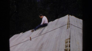 1957: a man working on a wooden roof, who appears to be pounding in nails