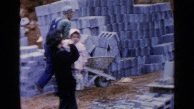 1957: group of people working together to build a concrete block wall