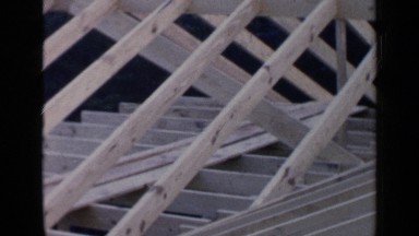 1957: two men working hard and building a wooden structure in the forest