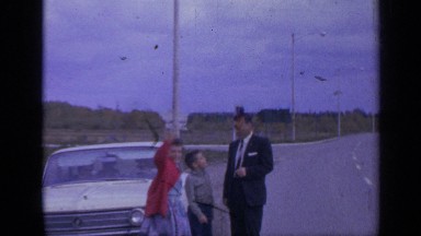 1959: near to a parked car along the roadside a family stands and walk away