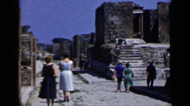 1960: tourists visit the remnants of a building with huge walls on a sunny day