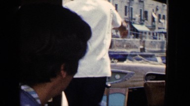 1960: a group passes through a small canal in a motorboat, a footbridges over