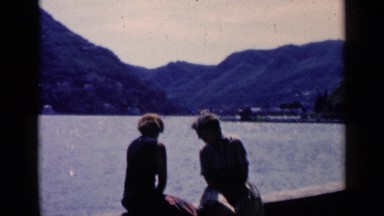 1960: two peoples are sitting in the wall near the river at morning time VENICE