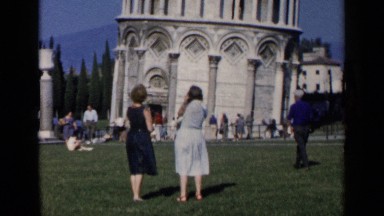 1960: two women stand in front of the leaning tower of pisa and other tourists