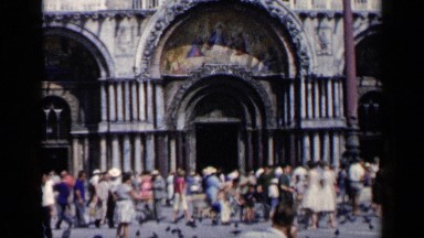 1960: Tourists Feed Pigeons in a Square in Front of a Building with Paintings