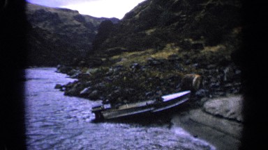 1963: panning view of beautiful mountain river with a boat on bank. IDAHO