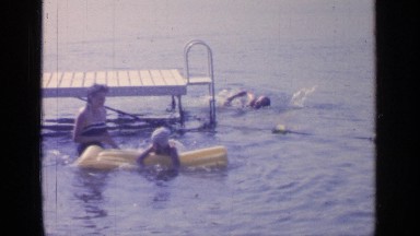 1964: different people use a rectangular, yellow, inflated float on the lake