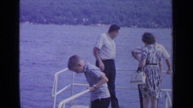 1964: family with a young boy standing on the deck of a boat with water