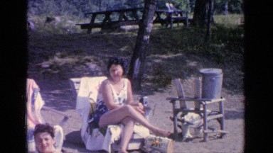1964: young people relax on sun lounges at the beach in their bathers. GREENWOOD