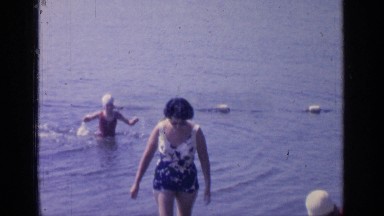 1964: Woman Leaves Lake by Carefully Wading Through Shallow Water to Shore