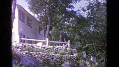 1964: a cottage is shown, then the camera cuts to a sign that reads "greenwood