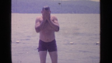 1964: a man wearing a bathing suit walks out of the swimming area of a lake