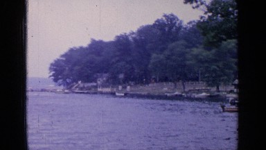 1964: panning view of a harbour and a boy fishing off a jetty. GREENWOOD LAKE