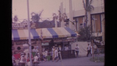 1964: people walking and sitting down at a outdoor festival.