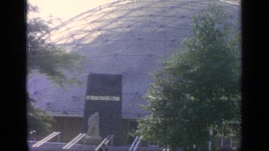 1964: people walking pas a dome shaped building that has statues