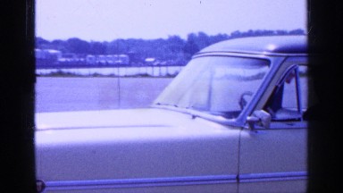 1965: a man sitting inside a car parked on the roadside LONG ISLAND NEW YORK