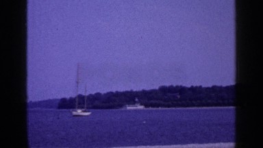1965: the camera slowly pans over a beach to the sea beyond on a sunny, summer