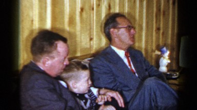 1965: grandpa holding grandchildren sitting on the sofa