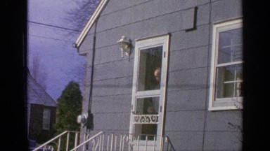 1965: older man looks out storm door at women, boy and cat outside his house