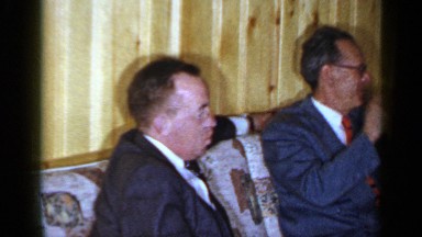 1965: Well-Dressed Men Sitting on a Wicker Couch Talking and Laughing Long Island