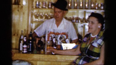 1965: man in hat serves two women drinks behind a home bar. LONG ISLAND NEW YORK