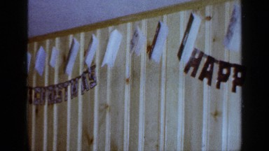 1965: brown-haired woman in a red top in a wood paneled room with decorations
