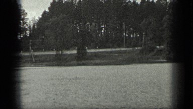 1939: Large grassland edged by coniferous trees with men standing
