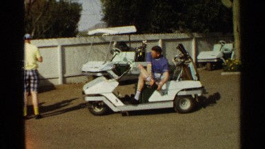 1968: man in golf cart smiles while tying his shoe. SCOTTSDALE ARIZONA