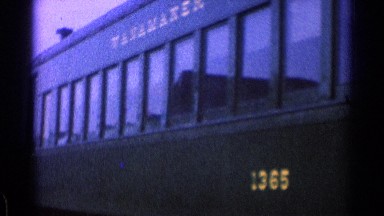 1976: Train Standing at Railway Station Surrounded by Open Fields and Low Hills