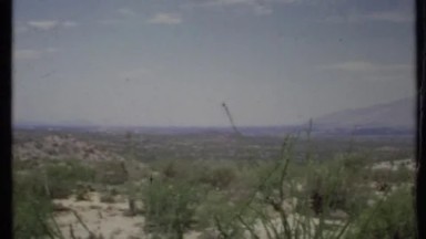 1971: a scenic view of the desert, it's plant life, and it's mountains.