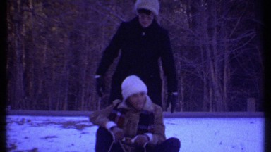 1979: a funny boy trying to push the sledge on the frozen shore lake with flock