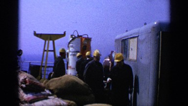 1970: yellow hard hat men walking slowly on a boat UNITED KINGDOM