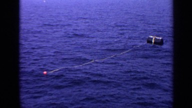 1970: inflated black can floating on the surface of water in the sea