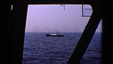 1970: a small vessel moving through the sea seen through window of a ship UNITED