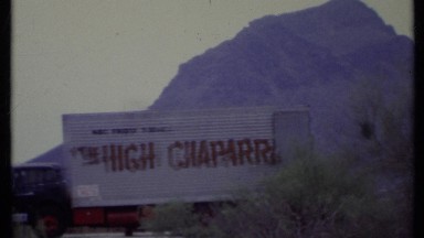 1971: panning footage of semi trucks against a backdrop of mountains and desert.