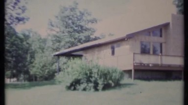 1971: a home has a large deck that looks out on a backyard during summer
