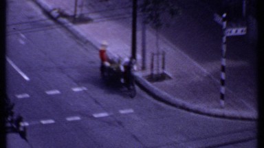 1969: Two Men Push a Bicycle Cart Through a Busy Intersection in Thailand