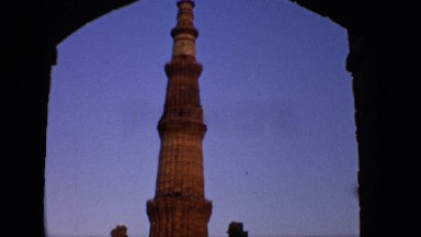 1970: a stone tower reaches into a blue sky as seen through a stone arch INDIA