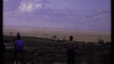 1969: people viewing at horizon far away close to a stable, enjoying sunset