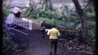 1969: two men cross primitive bridge and enter hut KENYA