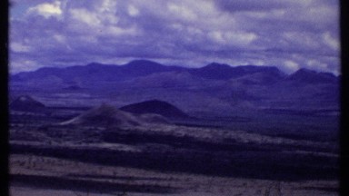 1969: man walks toward vw combi van with a beautiful mountain scene
