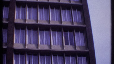 1969: video of tall building scanning upwards of window pattern and closed