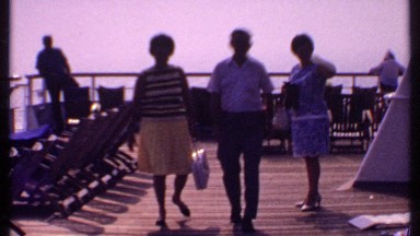 1969: Three People Talking and Walking While Two Stand Watching the Sea